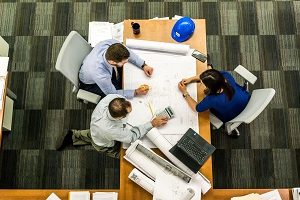 Three people working at table looking at drawings