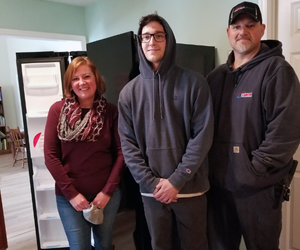 three people standing by a refrigerator