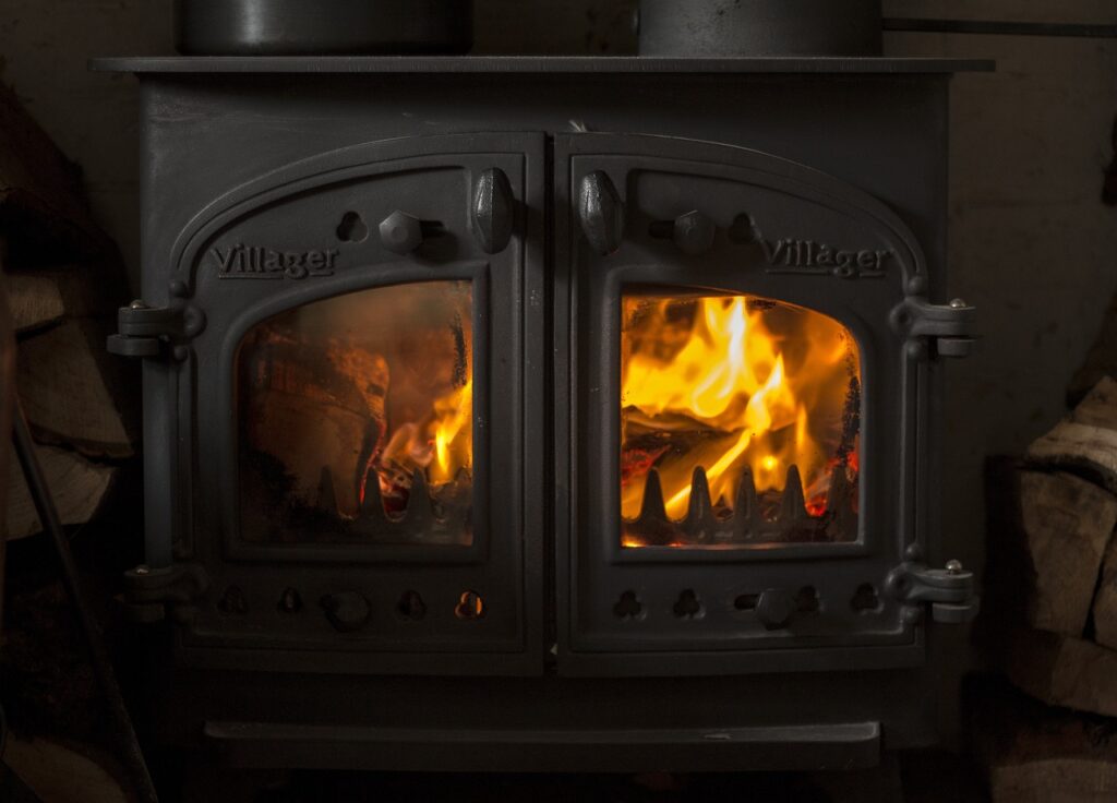 a wooden heating stove that has a cozy fire built.